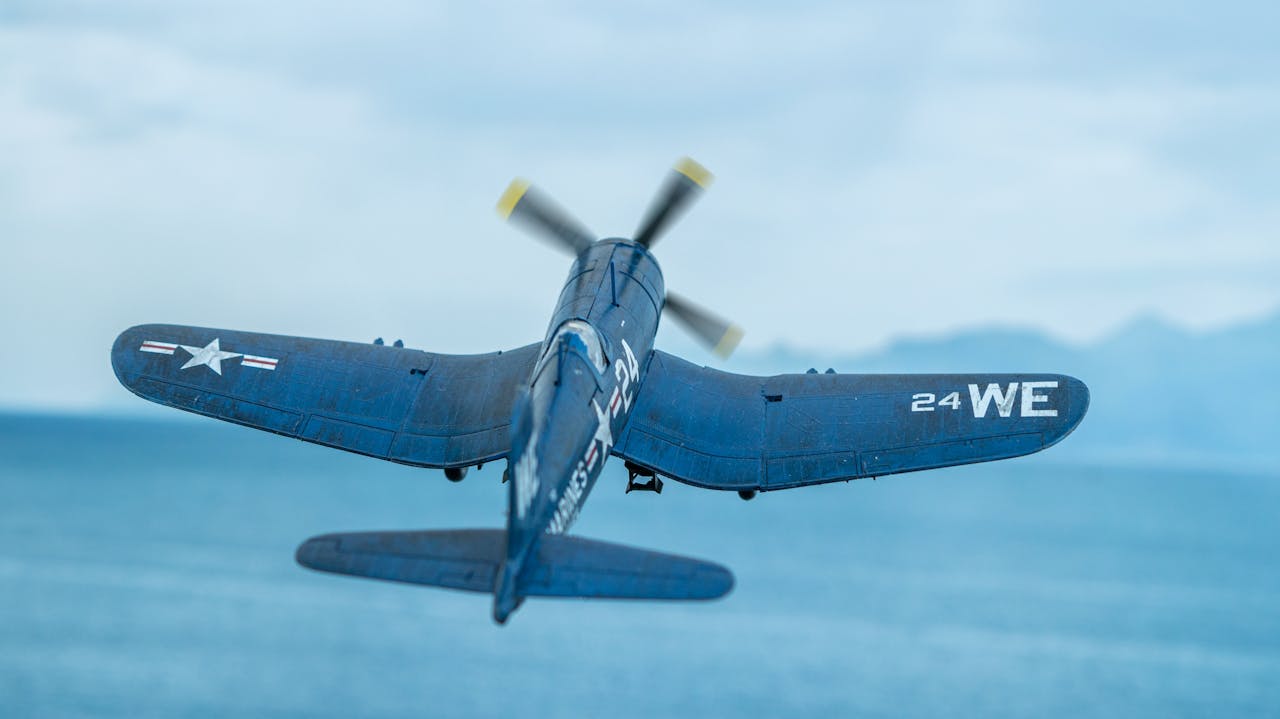 brand-02 Historic Vought F4U Corsair airplane in flight over ocean, seen from behind.